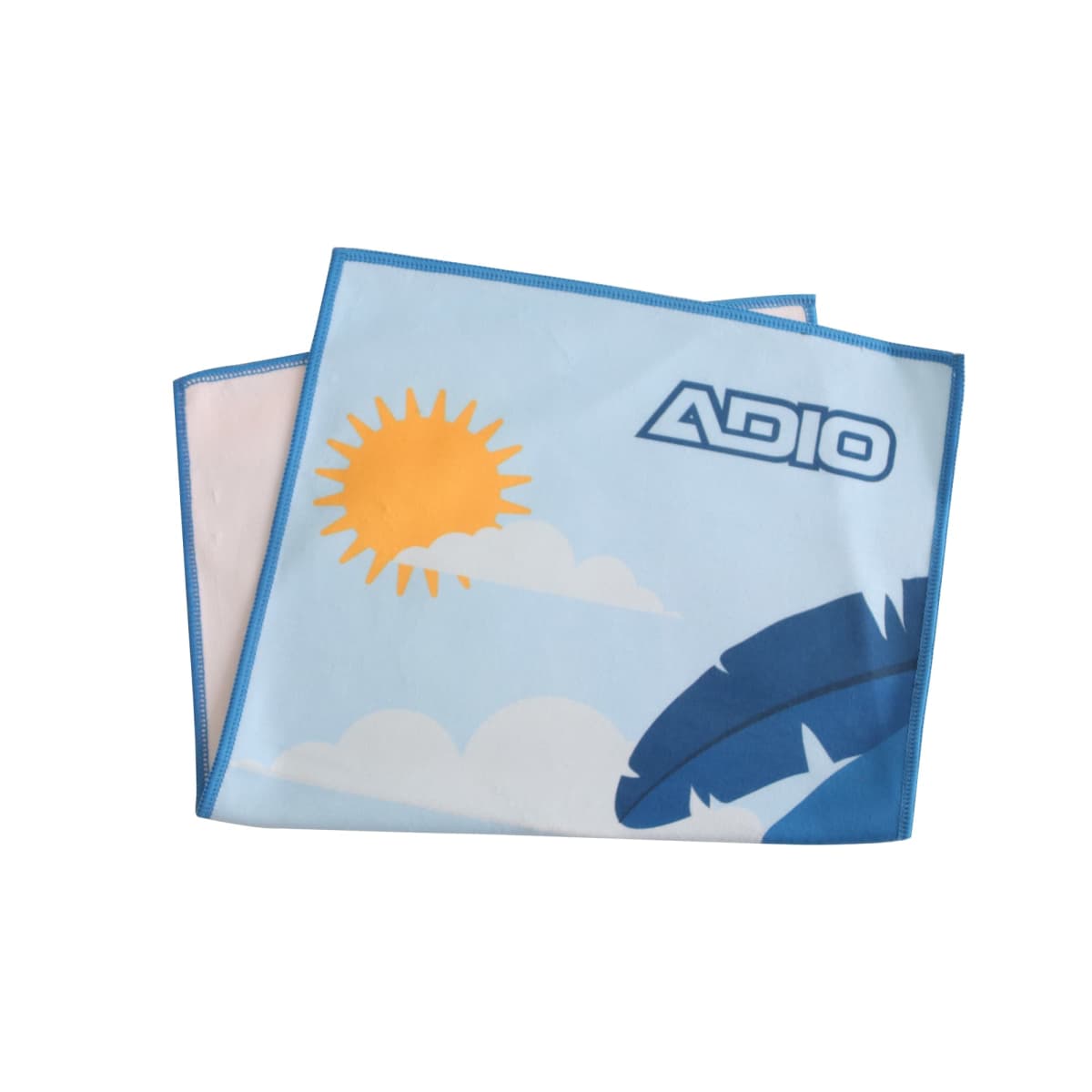 A folded blue towel featuring a sun, clouds, and blue abstract shapes. It has the word ADIO printed in dark letters on the upper right corner. The design gives a sunny, tropical vibe.