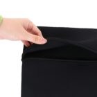 A hand wearing a green sleeve holds open a black zipper pocket. The zipper is partially unzipped, showing the edge of the pocket. The background is plain white.