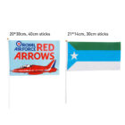 Two flags on white sticks. Left: Light blue with Royal Air Force Red Arrows and a red jet. Right: Green, white, and blue stripes with a white star. Dimensions: 20x30 cm (left), 21x14 cm (right), and sticks 40 cm and 30 cm respectively.