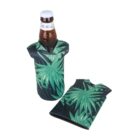 A brown glass bottle in a leaf-patterned koozie stands upright. Next to it is a matching flat koozie with the same green leaf design on a dark background.