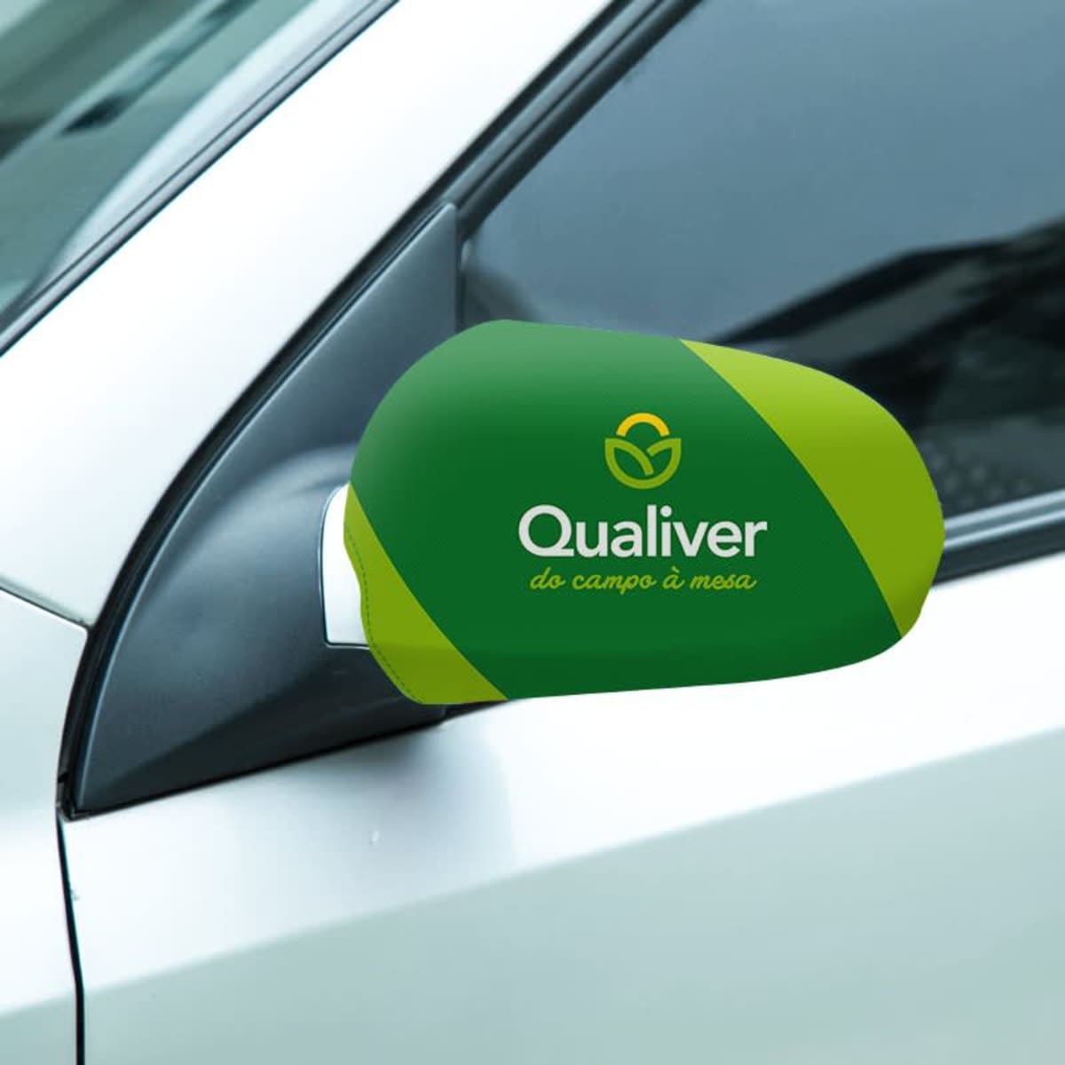 Car side mirror with a green cover featuring the logo and text Qualiver do campo à mesa in white. The cover is a bright green and dark green design, contrasting with the white car exterior.