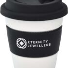 A reusable white coffee cup with a black lid and sleeve. The sleeve features the logo and text Eternity Jewellers.