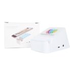 White wireless speaker with built-in phone holder and colorful logo, placed next to its packaging box. The box shows an image of the speaker with a phone docked on it. The device features buttons and connection ports on the side.