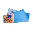 Colorful beach towel featuring a design with blue water, a sandy beach, a blue and red kayak, and green tropical leaves on one side. The towel is folded neatly against a plain white background.