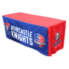 A table covered with a blue and red cloth featuring the Newcastle Knights logo, a stylized knight helmet, and text reading Newcastle Knights and Knights Membership: Play Your Part. The cloth drapes over the front and sides of the table.