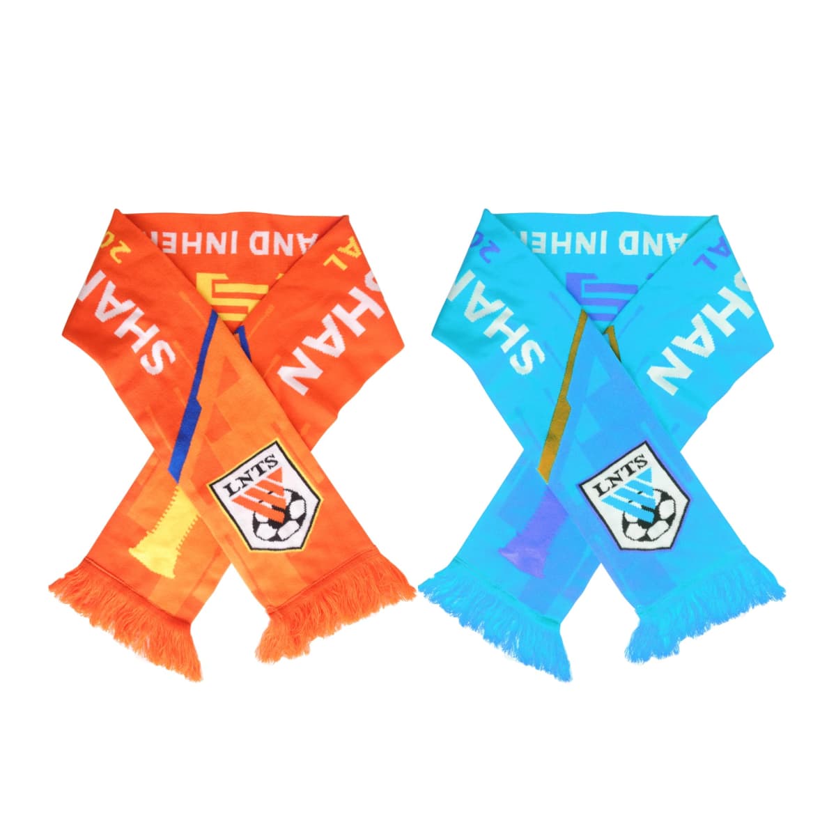 Two overlapping scarves, one orange and one blue. Each features the text SHAH with a shield emblem containing a soccer ball at the bottom. Fringed ends are visible on both scarves.