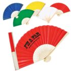 A set of colorful folding hand fans displayed in red, blue, green, yellow, and white. The red fan is prominent, featuring the text IM A FAN on it. Each fan has a wooden framework and is partially open.