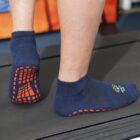 Person walking on a treadmill wearing navy blue socks with red grip patterns on the soles.