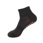 A black ankle-length sock with pink non-slip grips on the bottom, displayed against a white background.