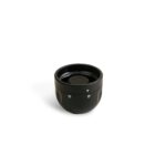 A black, round, cylindrical object with a hollow interior, featuring two small icons and a triangular symbol on its surface, set against a plain white background.