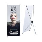 A promotional banner stand displays a fashion advertisement featuring a model with bold makeup. Text reads: SALE UP TO 50% OFF. Starts Tomorrow 4th December at Haute. True Style Never Dies. The stand is shown from both front and back views.
