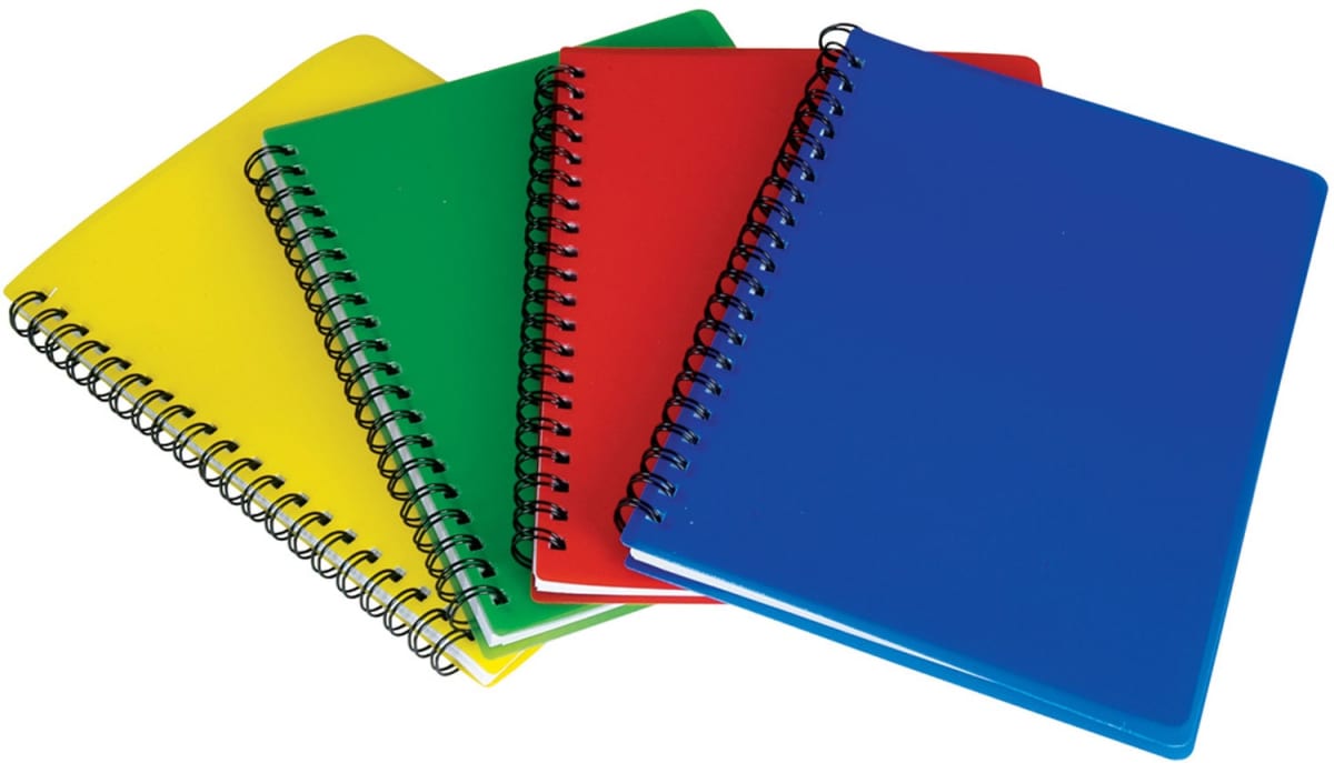 Four spiral notebooks are arranged in an overlapping pattern. They have colorful covers: yellow, green, red, and blue. The spiral bindings are black, and the notebooks are positioned on a plain, light-colored surface.