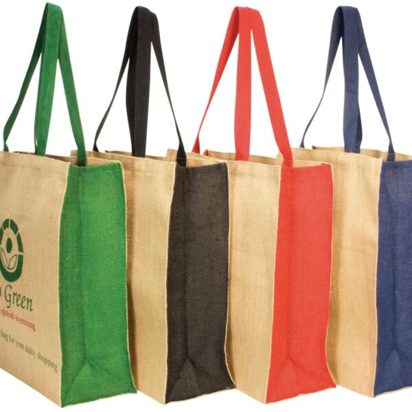 Five eco-friendly jute shopping bags with colored handles: green, black, red, brown, and blue. The green bag has a Go Green logo and message, while the others are plain. The bags are aligned side by side.