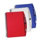 Three spiral-bound notebooks with attached pens are stacked. The top notebook is red with a red pen, the middle is white with a white pen, and the bottom is blue with a blue pen.