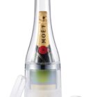 A bottle of Moët champagne is encased in a clear, bottle-shaped ice mold. The mold has a handle-like top and a detached cap beside it.