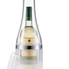 A bottle of white wine is enclosed in a transparent, plastic cooling container shaped like an oversized bottle. The cooler has a separate base and lid for opening. The bottles label is partially visible through the container.