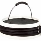 A white collapsible laundry basket with a black fabric body and a black zippered cover. The basket has a metal handle with a black grip and a silver ring attached to the side.