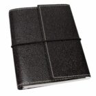 A closed, black leather-bound journal with textured cover, secured by an elastic band. The journals edges are neat, and it has white stitching along the border, giving it a refined, classic appearance.