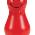 A red, smiling, pear-shaped plastic toy with a smiley face and simple facial features. It has a glossy finish and resembles a classic toy used for balancing or wobbling.