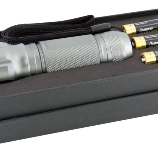 A silver, textured flashlight with a black wrist strap is placed in an open black box. Beside it are three AA batteries, showing their brand and design.
