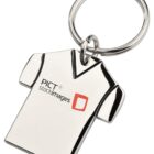A keychain shaped like a T-shirt with the text PICT stockimages and a red square logo printed on it. The keychain is made of shiny metal and is attached to a circular key ring.