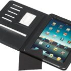 Black leather tablet case with a tablet displaying app icons, five card slots, and a clear ID slot on the left. A black cleaning cloth is placed in front.