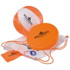An orange and white beach ball, an orange frisbee, a white drawstring bag with orange straps, and an orange pouch are displayed. All items are branded with Wild Real Cluj-Napoca. A small keychain with a round blue and white disc is also included.