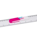 A transparent ruler with clear measurement markings is placed diagonally. Two erasers, one pink and one white with blue, are laid on top of the ruler.