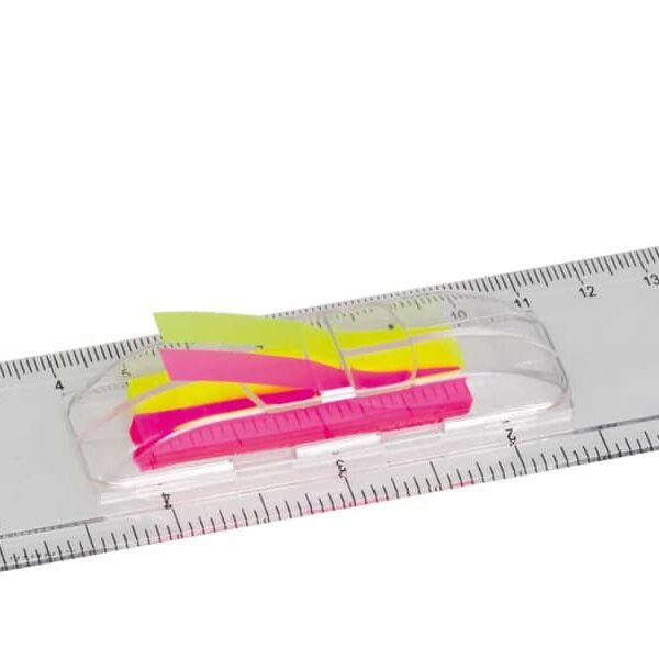 A transparent plastic ruler displaying both centimeters and inches. Attached in the center are pink and yellow adhesive index tabs.