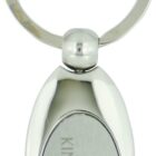 Silver oval keychain with an engraved panel. The panel features the text KINGSGATE and HAMILTON, along with a vertical line logo. The keychain has a smooth, shiny finish and a circular key ring attached.