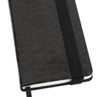 A closed black notebook with a textured cover resembling reptile skin. It has a black elastic band around it and a ribbon bookmark.