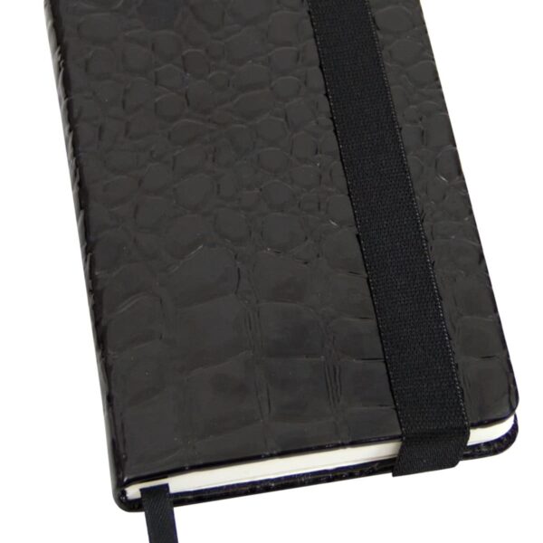 A closed black notebook with a textured croc pattern cover and an elastic strap. A ribbon bookmark peeks out from the bottom.