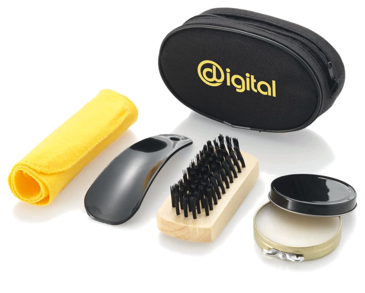 A grooming kit with a black zippered pouch labeled digital, a yellow cloth, a black glossy shoehorn, a wooden brush with black bristles, and a small round tin container, all arranged neatly.