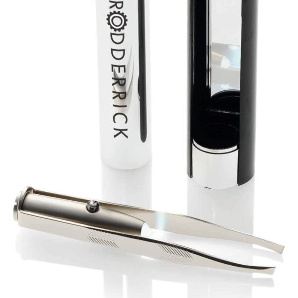A sleek metallic tool with precision tips lies next to an open cylindrical case labeled RODDERICK. The cases lid is positioned upright beside it. The tool reflects light, emphasizing its polished surface.
