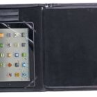 An open black leather folio case displaying a tablet on the left side. The tablet shows various app icons on its screen. The right side of the case is empty, featuring a dark, soft interior.