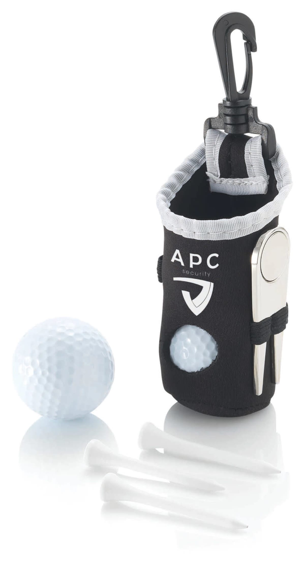 A small black golf accessory pouch with a carabiner clip, labeled APC, holds a white ball marker, a divot tool, and three golf tees. A white golf ball is positioned next to the pouch.