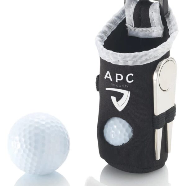 A black and gray pouch with a clip, branded APC Security, holds a metal divot tool and two wooden tees. Nearby are three additional tees and a white golf ball.