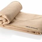 A neatly folded, light brown fleece blanket with the text La Roche University embroidered in black on one corner, placed against a plain white background.
