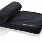 A rolled-up, black fleece blanket with LaRoche University embroidered in white text on the corner, placed on a white surface.