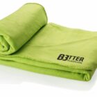 A neatly folded, bright green fleece blanket with stitching along the edges. The words BETTER PLACES.COM in black are printed on one corner.