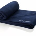 A neatly folded, dark blue fleece blanket with La Roche University embroidered in white on one corner. The blankets edges are slightly visible, showing a soft texture.