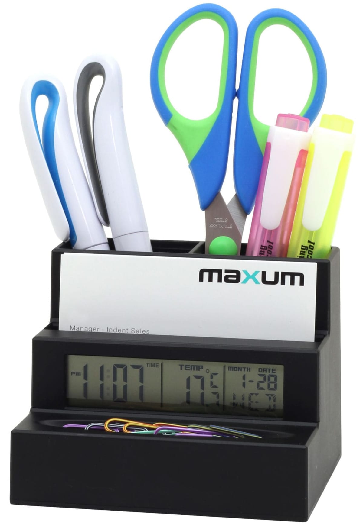 A black desk organizer holding blue and green scissors, pens, highlighters, and a business card. The base features a digital clock displaying time, temperature, and date, with colorful paperclips arranged in front.