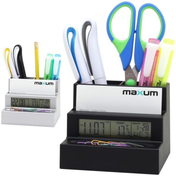 Two desktop organizers with digital clocks display time, temperature, and date. Each organizer holds pens, scissors, and highlighters. One is white, the other black, both with the brand maxum. Paperclips are placed in front of the clocks.
