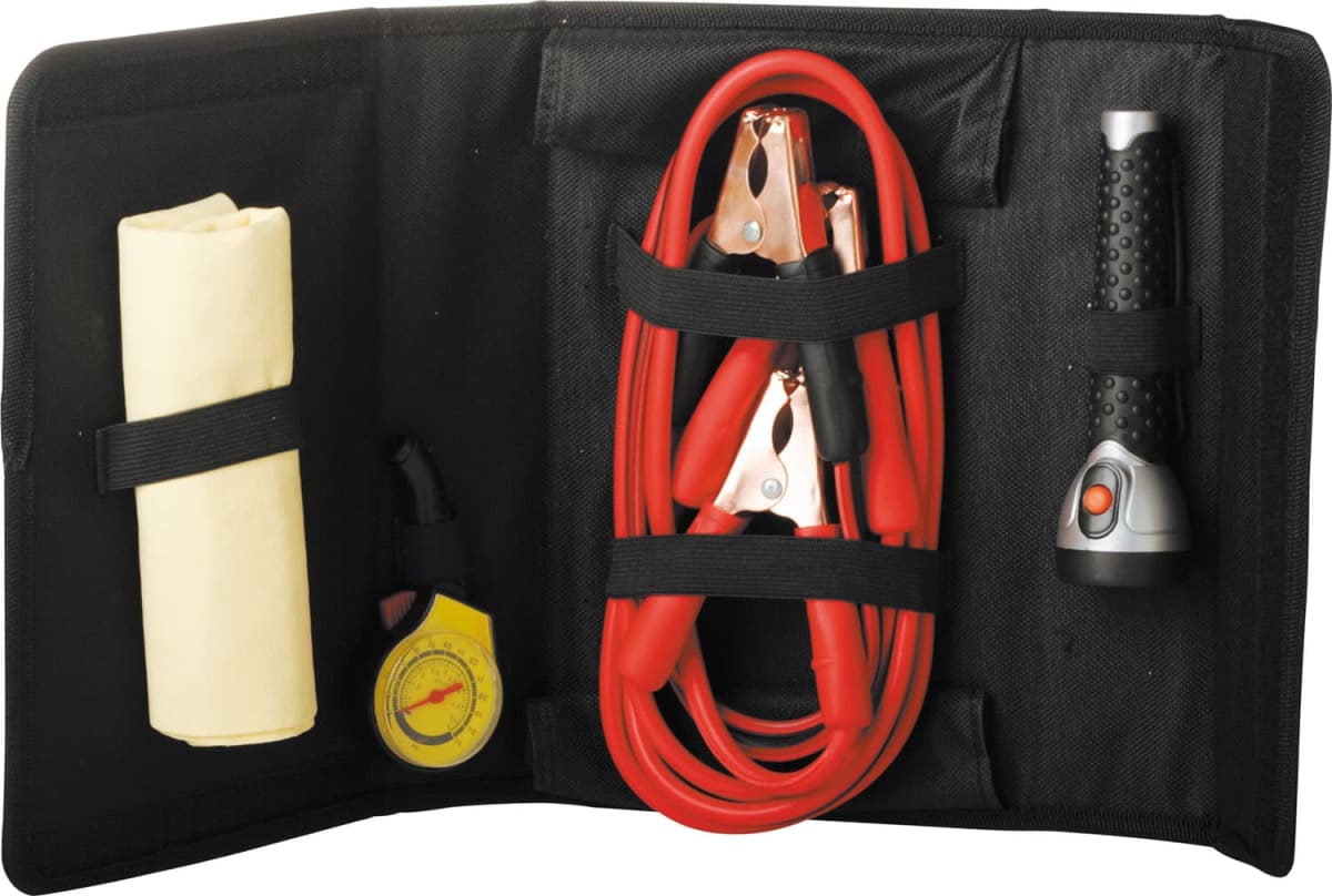 A black tool kit contains a yellow cloth, a tire pressure gauge, red jumper cables with clamps, and a black flashlight. Each item is secured in its own compartment within the kit.