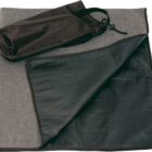 A folded grey and black blanket with a waterproof underside is displayed with a small black drawstring bag placed on top.