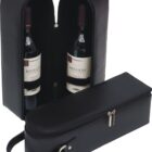 A black leather wine carrier is open, revealing two bottles of red wine inside labeled Mission. Another similar closed carrier, with a handle and zipper, is in front of it.
