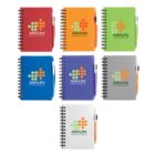 A collection of seven spiral-bound notebooks in various colors (red, orange, green, blue, purple, gray, and white), each with AWLIN Technical School on the cover. Each notebook has a pen attached on the side.