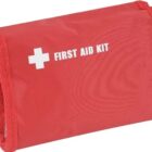 A red first aid kit with a white cross and the words FIRST AID KIT printed on the front. The kit is rectangular with textured fabric edges.