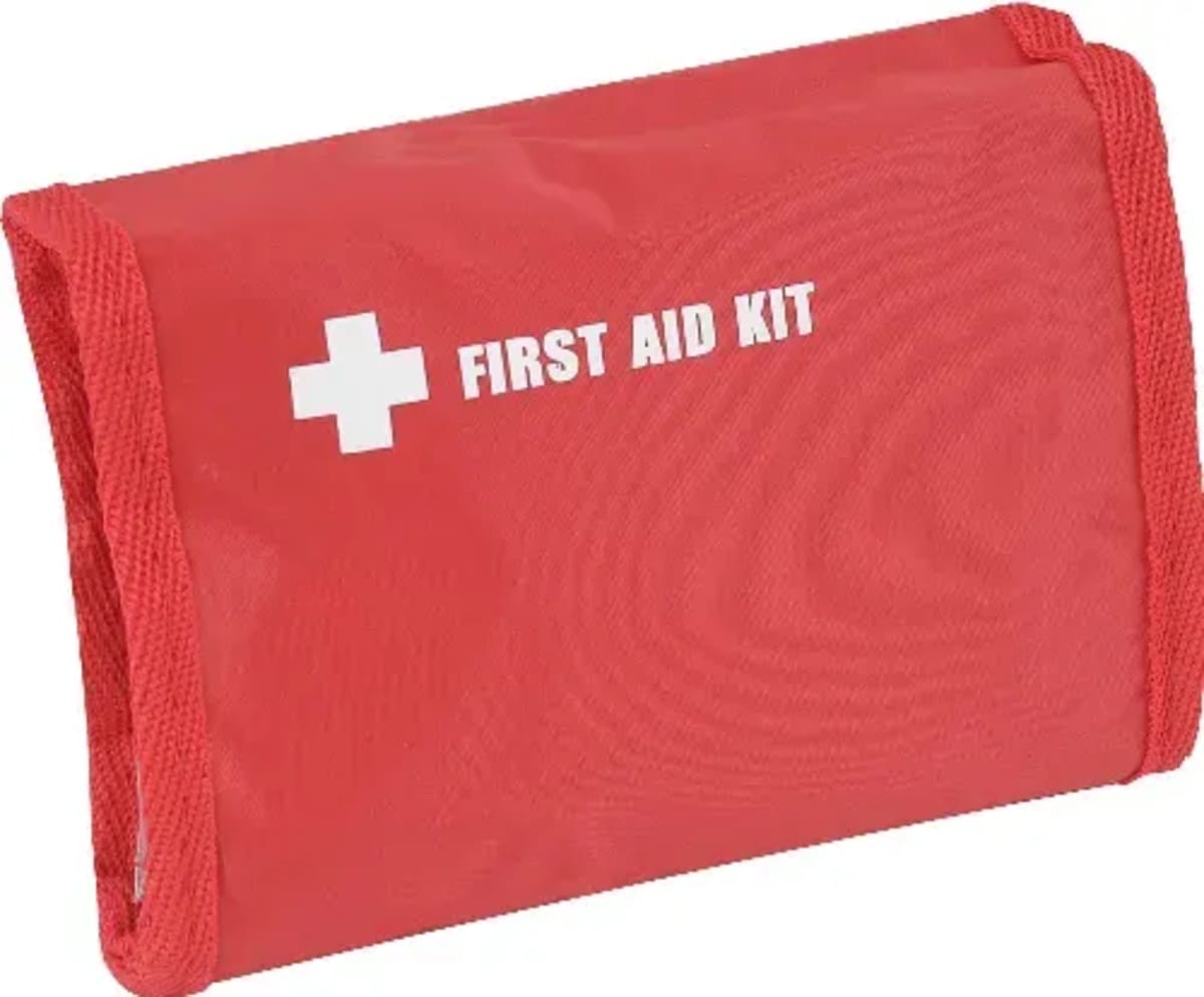 A red first aid kit with a white cross and the words FIRST AID KIT printed on the front. The kit is rectangular with textured fabric edges.