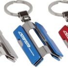 Three metallic keychains, each shaped like a miniature stapler, are displayed. They come in silver, blue, and red, with the word STAP-STEP printed on each. All have a ring attachment for holding keys.
